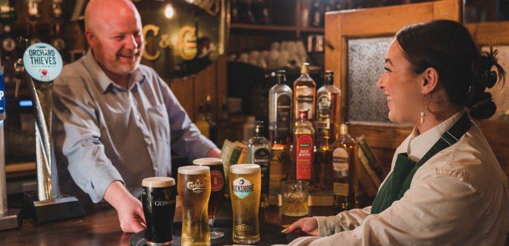 bartender and waitress serving pints of Guinness, Carlsberg, Rockshore and smitchwicks at The Crowes Nest Enniskillen