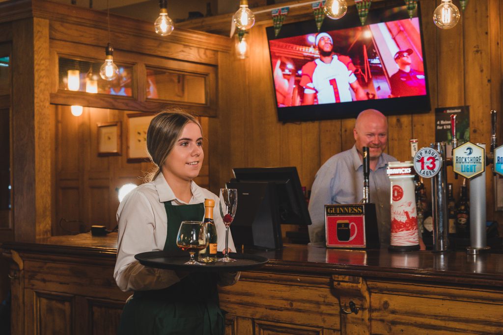 live spor on the television, bartender preparing frings and waitress serving at the crowes nest