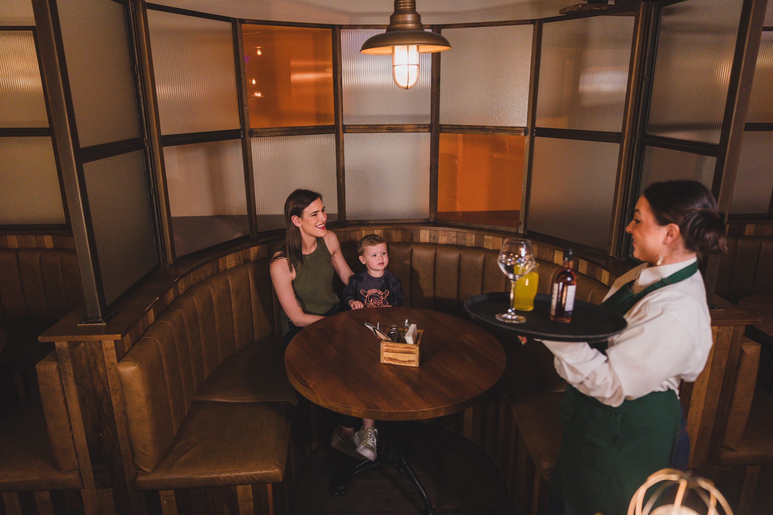 mother and child sitting in a booth at The Crowes Nest being served drinks by waitress Gluten free dining Enniskillen Crowes Nest Enniskillen menu